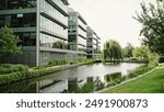 Modern office complex with glass fronted buildings in a scenic landscaped garden with pond ad reflections.