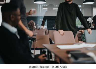 A modern office environment captures a diverse team of business professionals engaging in a collaborative discussion during a casual meeting setup. - Powered by Shutterstock