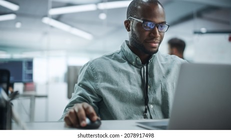 Modern Office: Portrait of Happy Black IT Programmer Working on Laptop Computer. Male Specialist Create Website, Software Engineer Develop App, Program, Video Game. Stress Free Inclusive Environment - Powered by Shutterstock