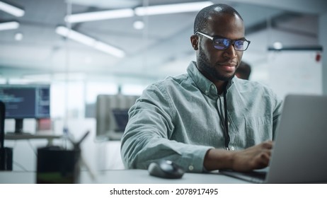 Modern Office: Portrait Of Motivated Black IT Programmer Working On Laptop Computer. Male Specialist Create Website, Software Engineer Develop App, Program, Video Game. Stress Free Inclusive Space