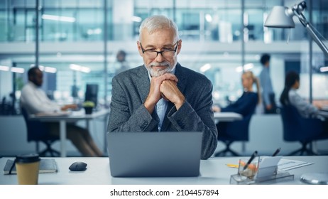 Modern Office: Portrait Of Successful Middle Aged Bearded Businessman Working On A Laptop At His Desk. Smiling Corporate Worker. Multi-Ethnic Workplace With Happy Professionals. Front View Shot