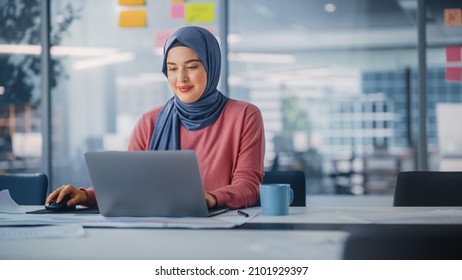 Modern Office: Portrait Of Young Muslim Businesswoman Wearing Hijab Works On Laptop, Does Data Analysis, Website Design, Creative Development. Digital Entrepreneur Works On E-Commerce Startup Project