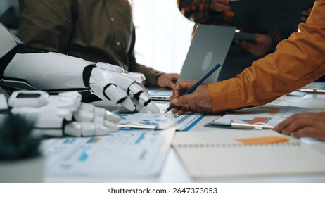A modern office scene showcasing collaboration between a human and a robot, highlighting data analysis, teamwork, and innovative technologies in a dynamic work environment.Noogenesis