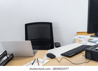 Modern office setup featuring a desk, laptop, monitor, keyboard, and an empty chair