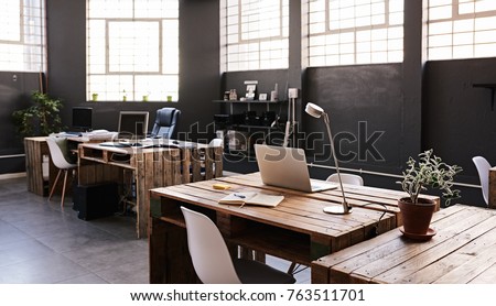 Modern office space with tables and chairs, computers and office supplies with no employees 