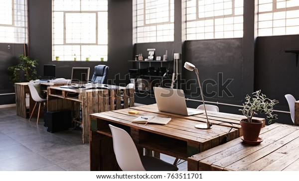 Modern office space with tables and
chairs, computers and office supplies with no employees
