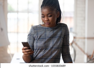 In modern office workplace african woman using smartphone send sms, businesswoman company worker check agenda, watching plan for day on calendar, browse internet before business meeting start concept