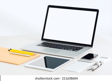 Modern office workplace with metallic laptop, digital tablet, mobile phone, papers, notepad and others business objects and items lying on a desk. Isolated on white background. - Powered by Shutterstock