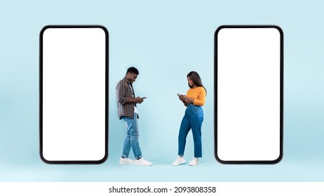 Modern Online Communication. Full Body Length Of Happy Cheerful Black Couple Standing Near Two Big Huge Smartphones With White Empty Blank Screen Using Cell Phones, Chatting On Social Media, Blue Wall - Powered by Shutterstock