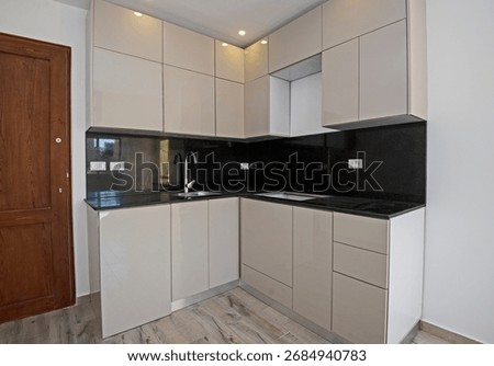 Modern open plan corner kitchen in an unfurnished apartment residence with black marble worktop
