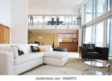 Modern open-plan apartment. Living room in foreground with kitchen to the rear and dining are on mezzanine deck above.