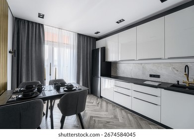 modern open-plan kitchen and dining area with light pink walls, gray cabinetry, dark wood floors, and a cozy rocking chair