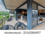 A modern, open-plan living space with a large balcony overlooking a pool. Lounge chairs and a hammock adorn the balcony.