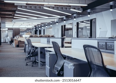 Modern open-plan office space featuring ergonomic workstations equipped with adjustable chairs and computer monitors mounted on desk arms. The design emphasizes clean lines and a neutral color palette