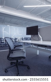 Modern open-plan office space featuring ergonomic workstations equipped with adjustable chairs and computer monitors mounted on desk arms.