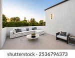 Modern outdoor patio with white sectional sofa and sleek design against a sunset backdrop.