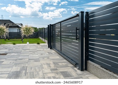 A modern panel fence in anthracite color, visible sliding gate to the garage and a slab driveway.