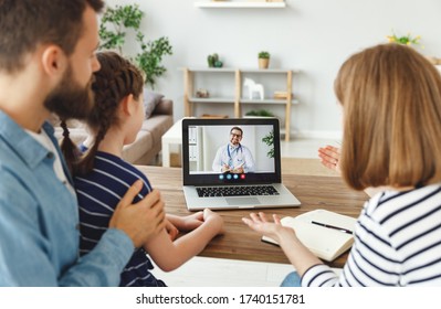 Modern Parents And Cheerful Daughter Sitting At Table And Speaking With Online Doctor At Home
