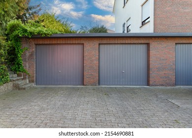 Modern parking garage in residential brick house for cars with grey roller shutters on gates. Closed doors in garages.
