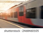 Modern passenger commuter train in motion at the railway platform at sunset. Railway station. Railroad with motion blur effect