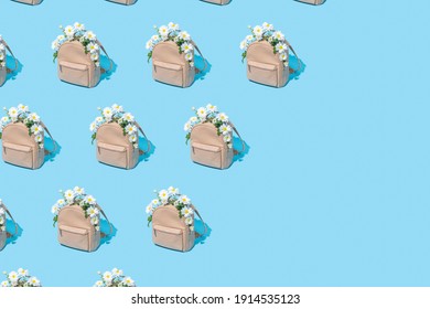 Modern Pattern Made Of School Bag Full Of White Daisy Flowers On Pastel Blue Background With Diagonal Copy Space. Back To School, Trendy Spring Semester Concept.