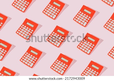 Modern pattern with vintage red calculators on sunny pink table.