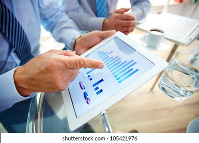 Modern people doing business, graphs and charts being demonstrated on the screen of a touch-pad