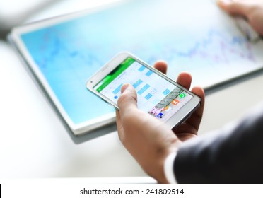 Modern people doing business, graphs and charts being demonstrated on the screen of a phone