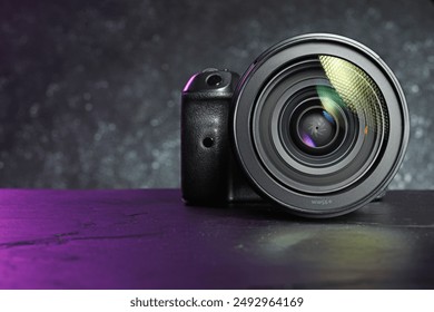 Modern photo camera on black table, space for text