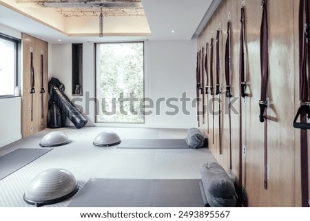 Modern Pilates studio designed for functional and suspension training.Room features large floor-to-ceiling windows that allow natural light to fill the space, creating a bright and inviting atmosphere