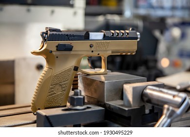 A modern pistol with a beige grip on a work table in a workshop. Service maintenance of weapons. Pistol repair.