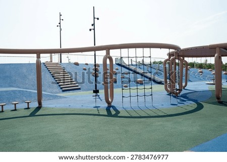Modern play structure with climbing elements and slides on rubber surface. Children playground and outdoor activity. Real photo.
