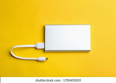 Modern Portable Charger With Cable On Yellow Background, Top View