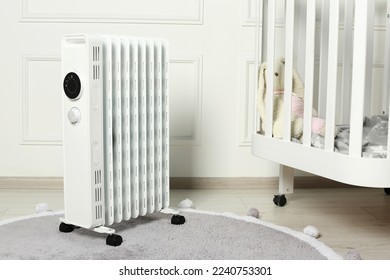 Modern portable electric heater and baby crib indoors