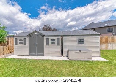 A Modern Premade Storage Shed On Fresh Green Grass Under The Cloudy Blue Sky