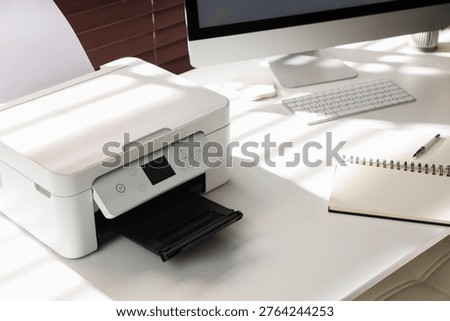 Modern printer, computer and stationery on white table in office, closeup