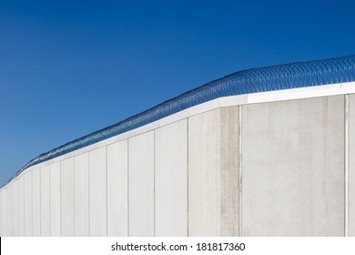 Modern prison wall against blue sky.
