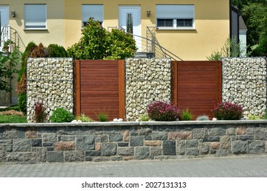 Modern Privacy Fence of Natural Rock Gabions, Wooden Boards and galvanized Steel Grid surrounding a residential Building (Germany)