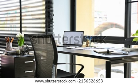 Modern private office workplace with notebook laptop computer and office supplies on table, office chair, document drawers and decor