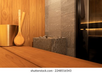 Modern private sauna for one person in apartment.  Interior with elegant stone electric heater, glass door and sauna accessories. 