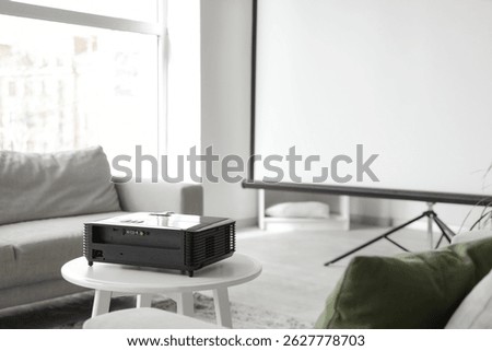 Modern projector on table in light living room, closeup