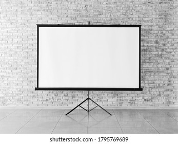 Modern Projector Screen Near Brick Wall Indoors