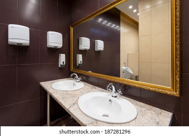 Modern Public Bathroom, Large Mirror In Washroom Interior. Dark Design Of Bathroom With Soap Dispenser. Clean Restroom With Brown Tile Decoration. Lavatory, Wc In Office.