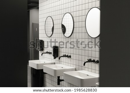 Modern public restroom minimal interior with metro style white tiles, round mirrors, black ceiling 