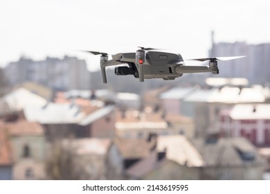 A Modern Quadcopter With A High Resolution Camera Hovering In The Air. A Compact Gray RC Drone Takes Aerial Photo Or Video Footage From The Air. Gadget In Flight Over The City. Drone Control.