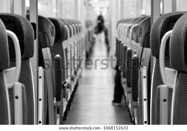 Modern railway coach interior illuminated and row\
of seats. Black and\
white