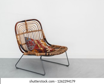 Modern Rattan Armchairs On Metal Legs With Colorful Mosaic Oriental Kilim Rug Pillow Folk Geometric Ornament On White Wall And Concrete Floor