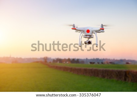 Modern RC Drone / Quadcopter with camera flying on a clear sunny sky sunset background with nice lens flare.