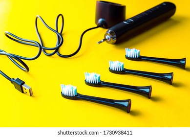 Modern Rechargeable Sonic Or Electric Toothbrush Set With Usb Charger And Heads On Yellow Flat Lay Background. Concept Of Professional Oral Care And Healthy Teeth By Using Ultrasonic Toothbrush