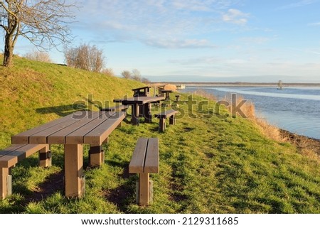 Modern recreation area, forest park, lake. Wooden benches, tables. Camping site. Soft sunlight, clear sky. Early spring. Idyllic landscape. Nature, environment, ecology, ecotourism, vacations, weekend